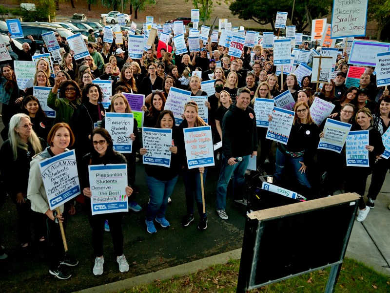 Members from the Association of Pleasanton Teachers pose with their picket signs on Oct. 26 in front of the Pleasanton Unified School District offices on Bernal Avenue after an hour of marching through downtown Pleasanton as a way to show solidarity with the union's requests for better pay and health benefits. (Photo by Chuck Deckert)